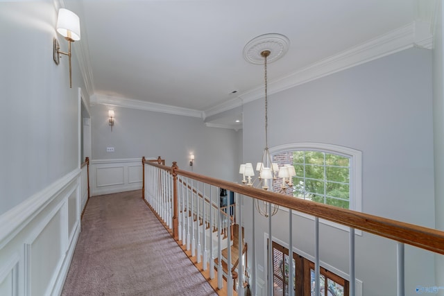 corridor with crown molding, an inviting chandelier, and light colored carpet