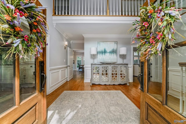 foyer entrance with crown molding, light wood-type flooring, and french doors