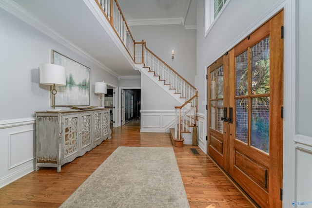 foyer entrance featuring a healthy amount of sunlight, ornamental molding, and light hardwood / wood-style flooring