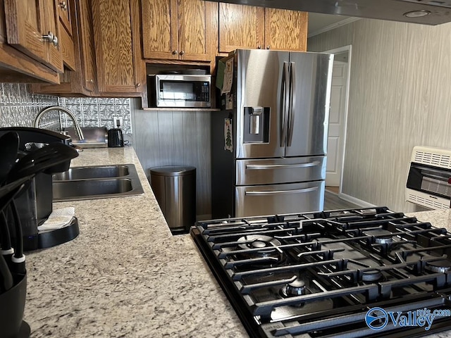 kitchen with stainless steel appliances, crown molding, heating unit, and light stone counters