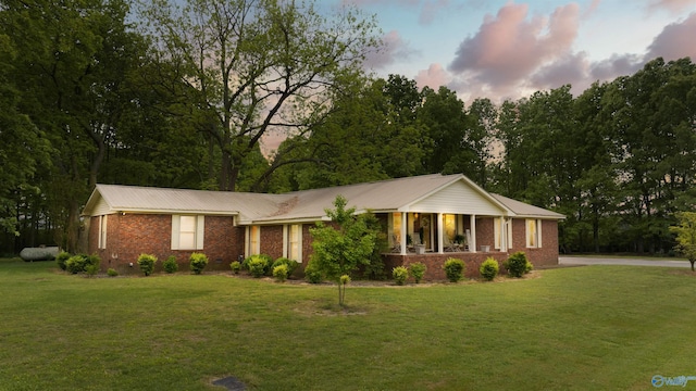 single story home featuring driveway, metal roof, a front yard, and brick siding