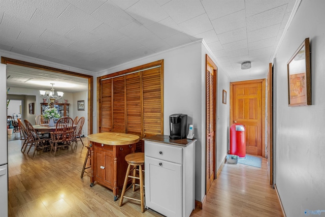 interior space with crown molding, light wood finished floors, baseboards, and a notable chandelier