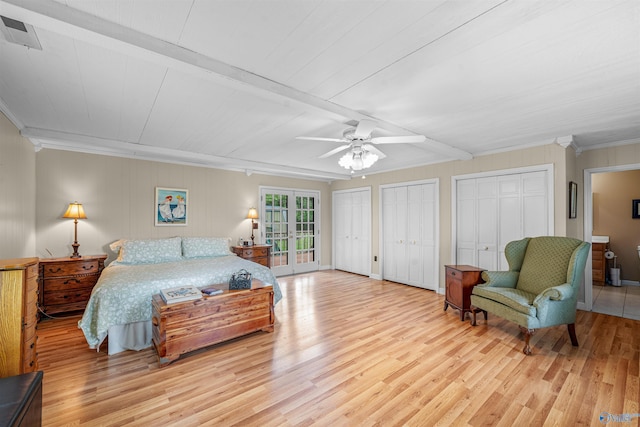 bedroom with beam ceiling, wood finished floors, two closets, and visible vents