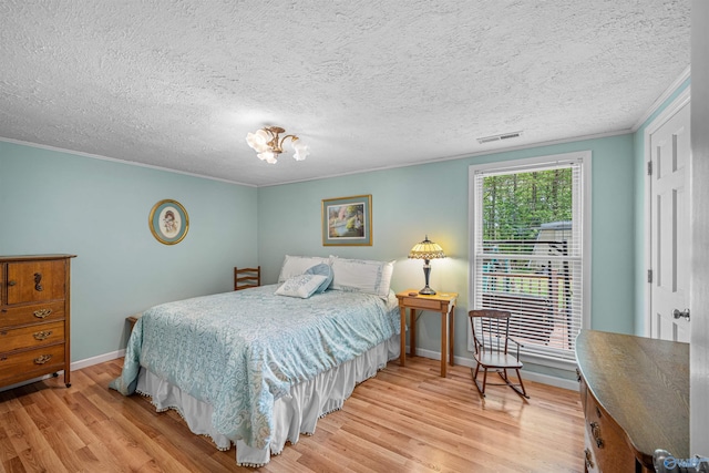 bedroom with ornamental molding, a textured ceiling, baseboards, and light wood-type flooring