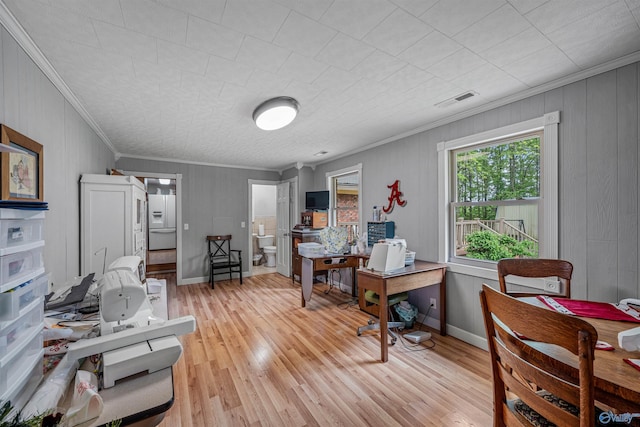 office area featuring crown molding, visible vents, wood walls, light wood-style flooring, and baseboards