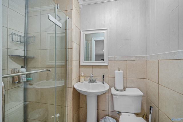 bathroom with toilet, tile walls, and a shower stall