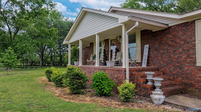 exterior space with covered porch, brick siding, and a yard