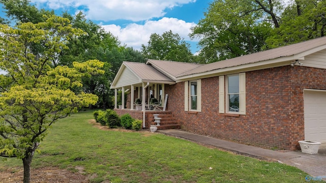 view of side of home featuring covered porch, a yard, an attached garage, and brick siding