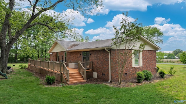 rear view of property with brick siding, a wooden deck, a yard, and crawl space