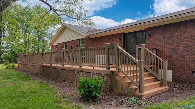 back of property featuring metal roof, a wooden deck, and brick siding