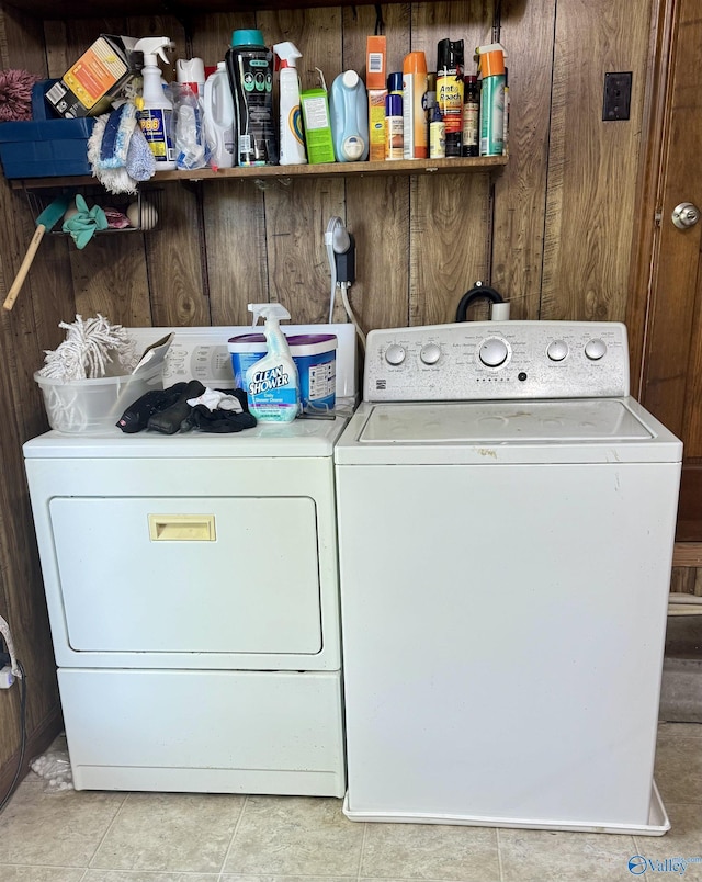 washroom with tile patterned floors, wooden walls, washer and dryer, and laundry area