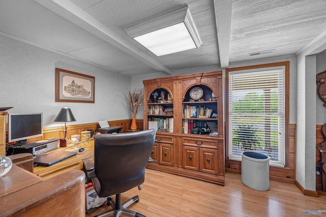 office with light wood-style flooring, visible vents, wainscoting, and beam ceiling