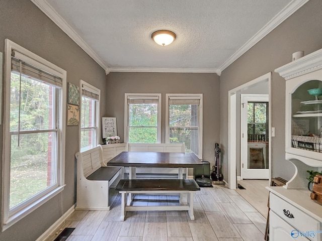 dining area with crown molding, plenty of natural light, a textured ceiling, and light wood-type flooring