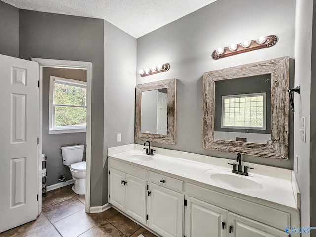 bathroom with tile patterned flooring, vanity, a textured ceiling, and toilet