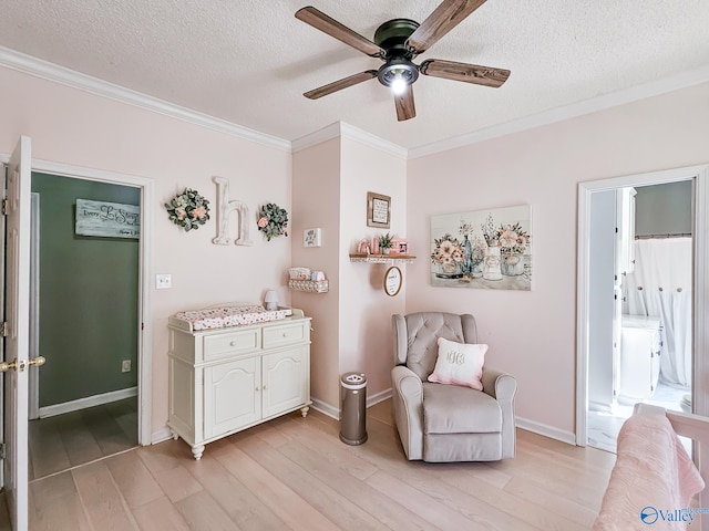 living area with ceiling fan, light hardwood / wood-style flooring, a textured ceiling, and ornamental molding