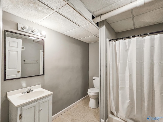 bathroom with tile patterned flooring, vanity, toilet, and a drop ceiling