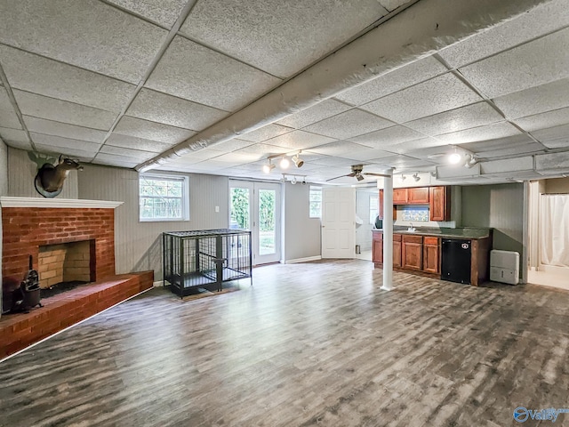 unfurnished living room with a paneled ceiling, ceiling fan, sink, a fireplace, and hardwood / wood-style floors