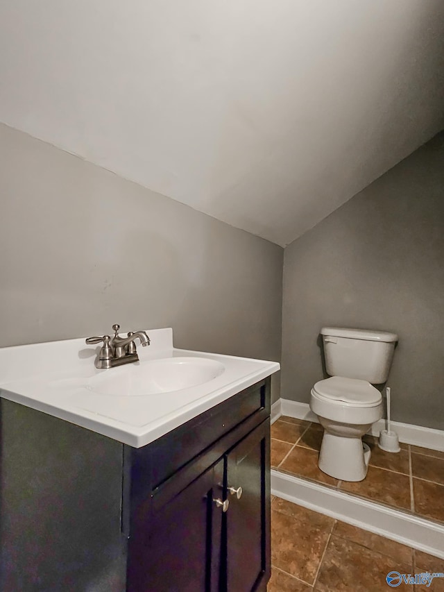 bathroom with tile patterned floors, vanity, lofted ceiling, and toilet