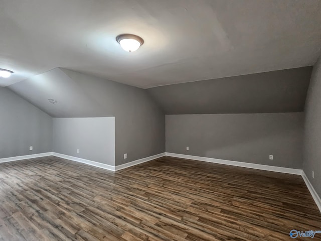 additional living space with vaulted ceiling and dark wood-type flooring