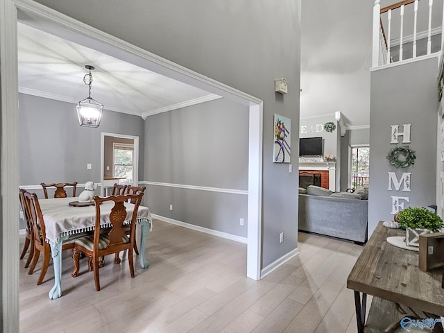 dining area featuring a chandelier, light hardwood / wood-style floors, a brick fireplace, and crown molding