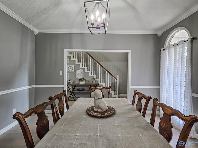 dining space featuring a textured ceiling, ornamental molding, and a notable chandelier