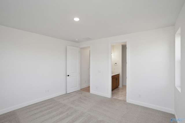 unfurnished bedroom featuring recessed lighting, baseboards, ensuite bathroom, and light carpet