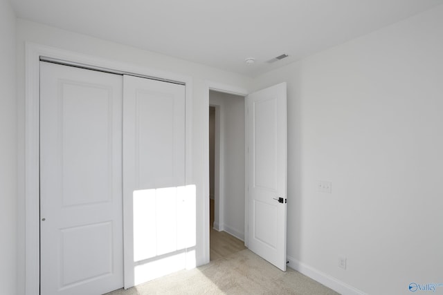 unfurnished bedroom featuring baseboards, visible vents, a closet, and light carpet