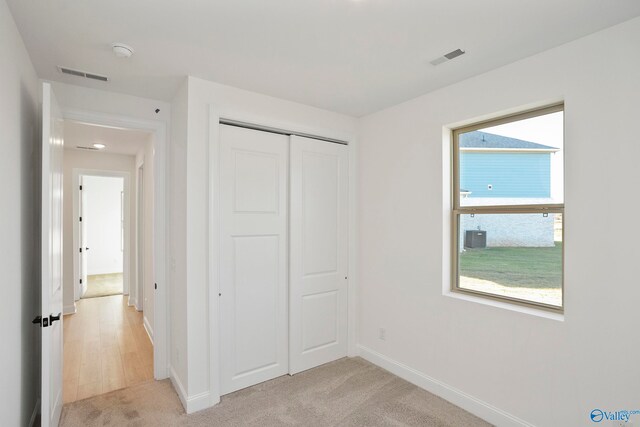 unfurnished bedroom with visible vents, light carpet, baseboards, and a closet