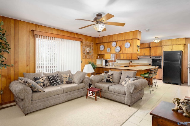 living room featuring visible vents, ceiling fan, wooden walls, and light tile patterned flooring