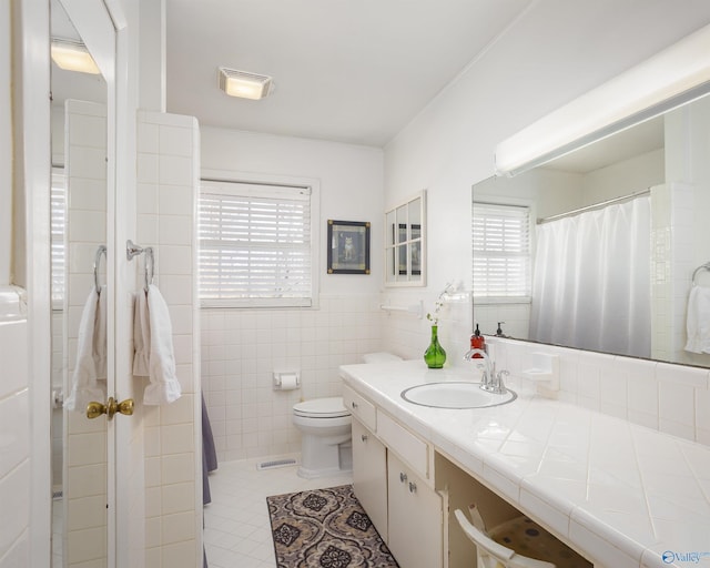 full bathroom with toilet, visible vents, vanity, tile walls, and tile patterned floors