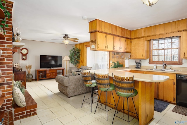 kitchen with black dishwasher, a kitchen breakfast bar, light countertops, a sink, and light tile patterned flooring