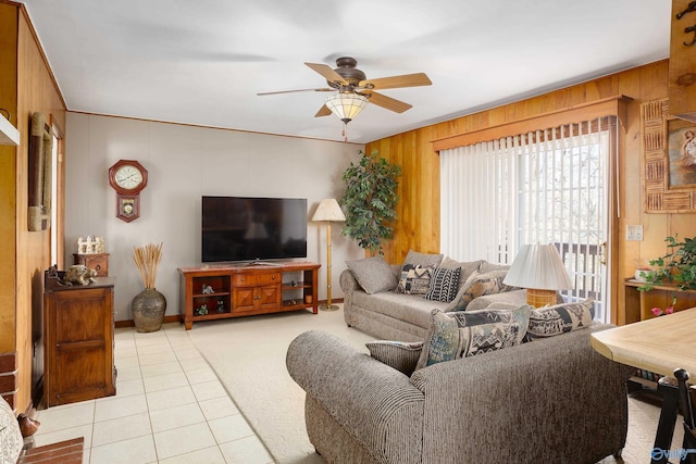 living room with a ceiling fan, wood walls, and light tile patterned floors