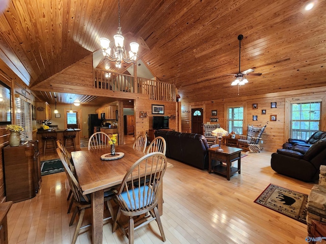 dining area featuring wood walls, ceiling fan with notable chandelier, wooden ceiling, light hardwood / wood-style flooring, and high vaulted ceiling