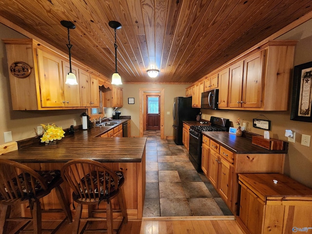 kitchen with sink, black appliances, dark hardwood / wood-style floors, kitchen peninsula, and a kitchen bar