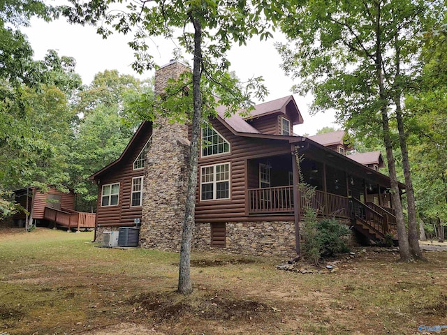 view of side of home featuring a wooden deck, a lawn, and central AC unit