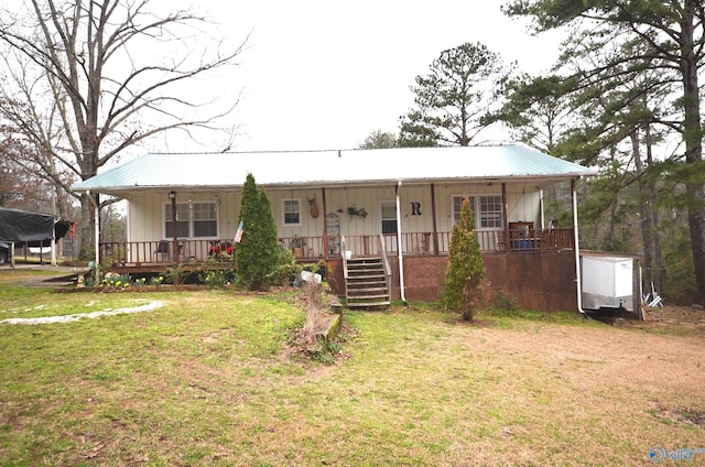 view of front of property featuring covered porch, metal roof, and a front yard