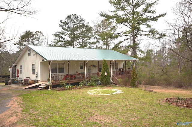 view of front of home featuring covered porch, metal roof, and a front lawn