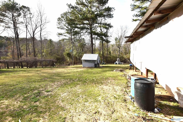 view of yard featuring a shed, a wooded view, and an outdoor structure