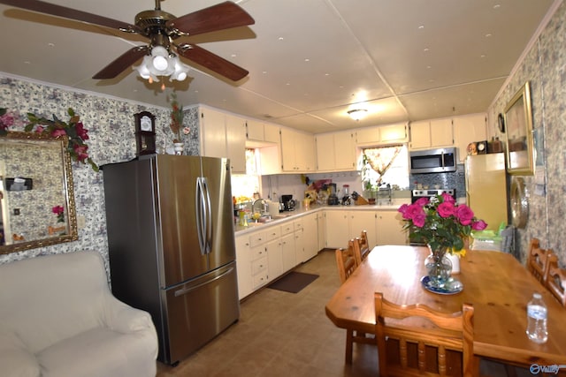 kitchen with white cabinets, ornamental molding, stainless steel appliances, light countertops, and a sink