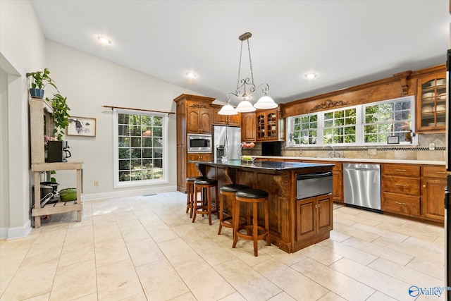 kitchen featuring a warming drawer, backsplash, appliances with stainless steel finishes, glass insert cabinets, and a kitchen island