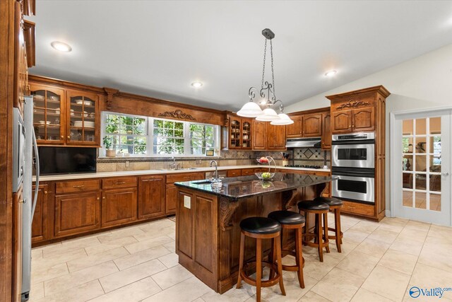 kitchen featuring tasteful backsplash, stainless steel appliances, sink, hanging light fixtures, and vaulted ceiling