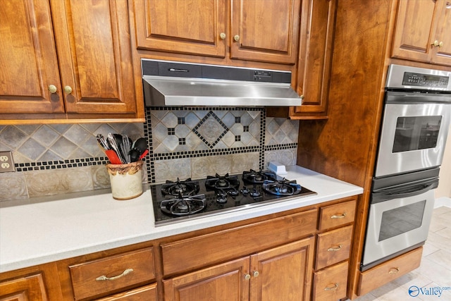 kitchen with double oven, light tile patterned floors, decorative backsplash, and black gas stovetop