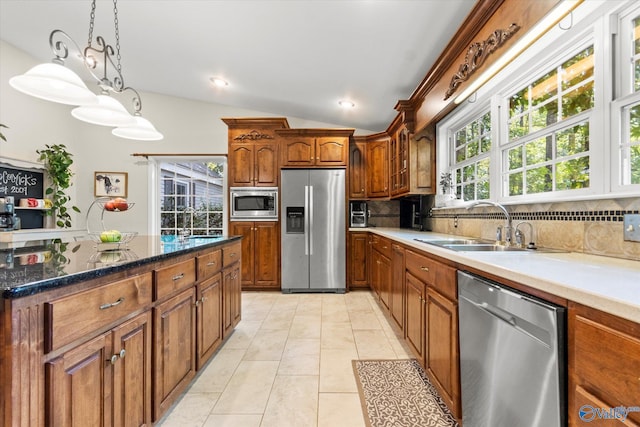 kitchen with stainless steel appliances, decorative backsplash, brown cabinetry, light tile patterned flooring, and a sink