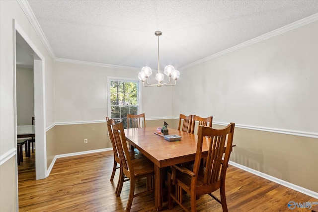 dining area with light wood-style floors, crown molding, a textured ceiling, and an inviting chandelier