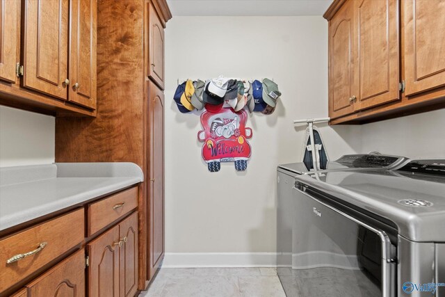 laundry room with light tile patterned flooring, cabinets, and washer and dryer