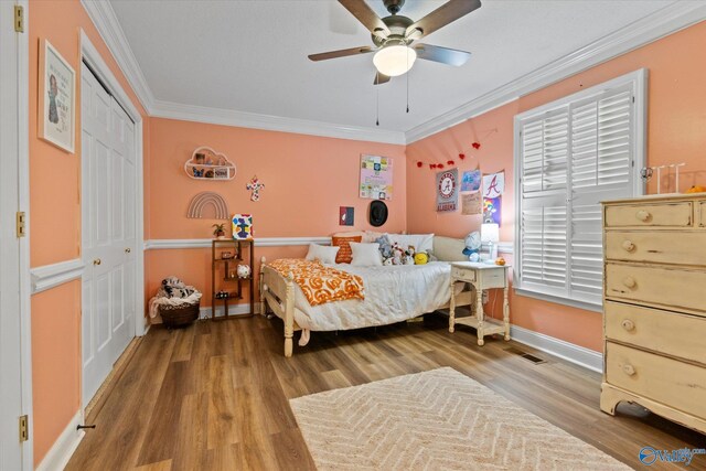 bedroom featuring hardwood / wood-style floors, ceiling fan, a closet, and crown molding