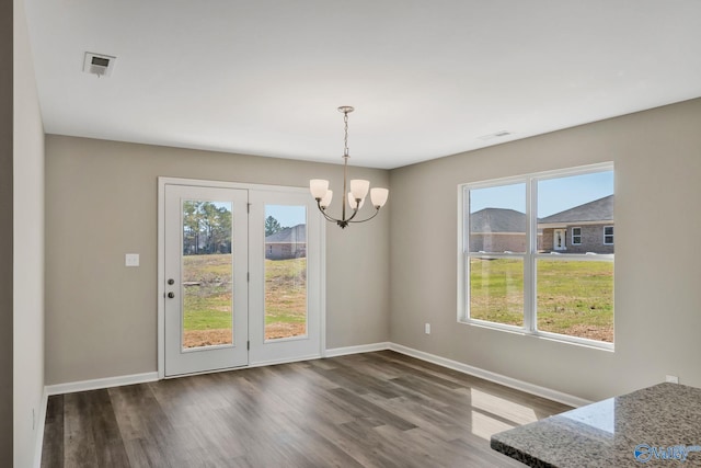 unfurnished dining area featuring visible vents, baseboards, a notable chandelier, and dark wood-style floors