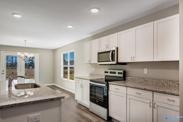 kitchen with a sink, appliances with stainless steel finishes, dark wood-style flooring, and white cabinetry