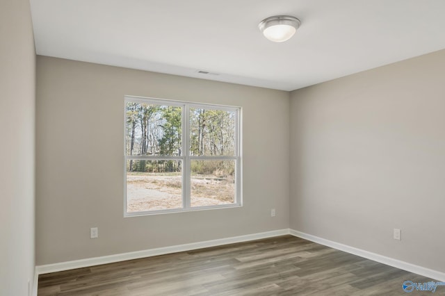 unfurnished room featuring visible vents, baseboards, and wood finished floors