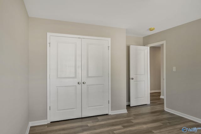 unfurnished bedroom featuring a closet, baseboards, and wood finished floors